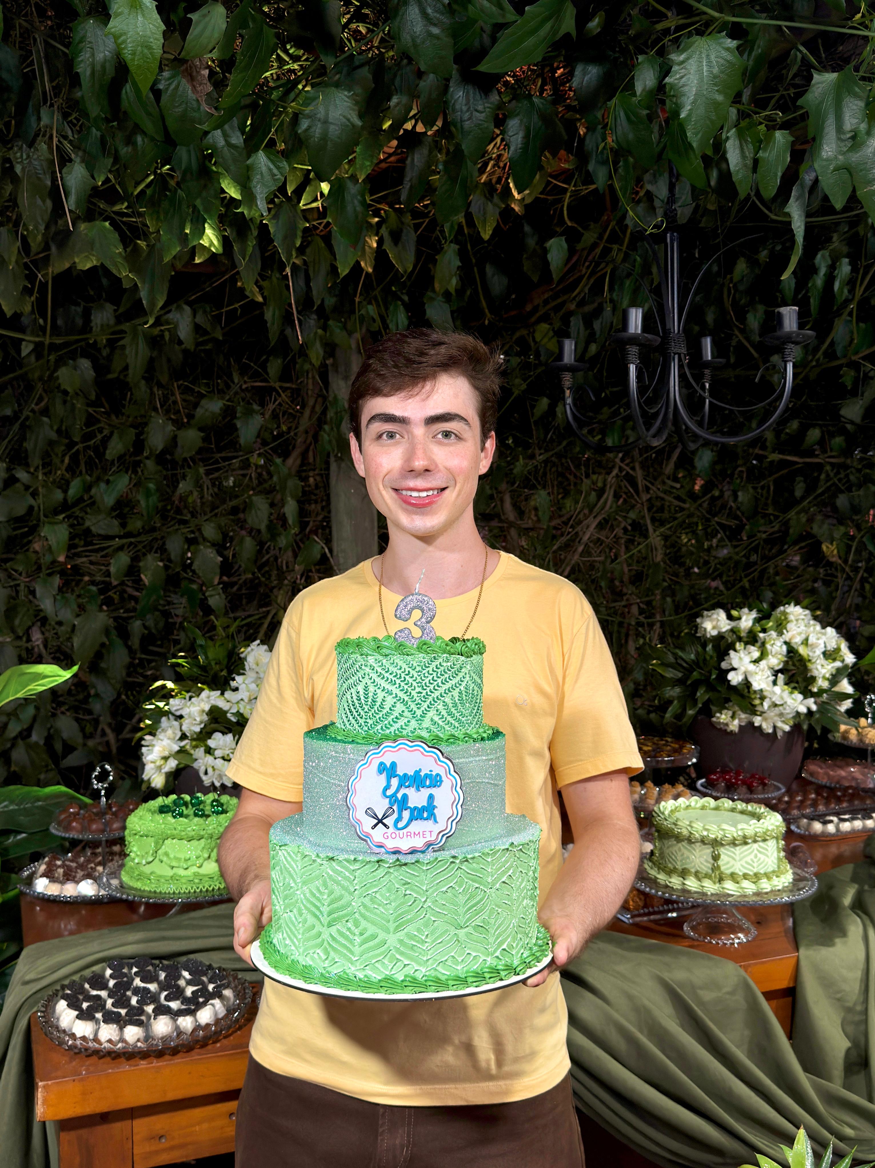 Benício Back, confeiteiro, segurando seu bolo de assinatura