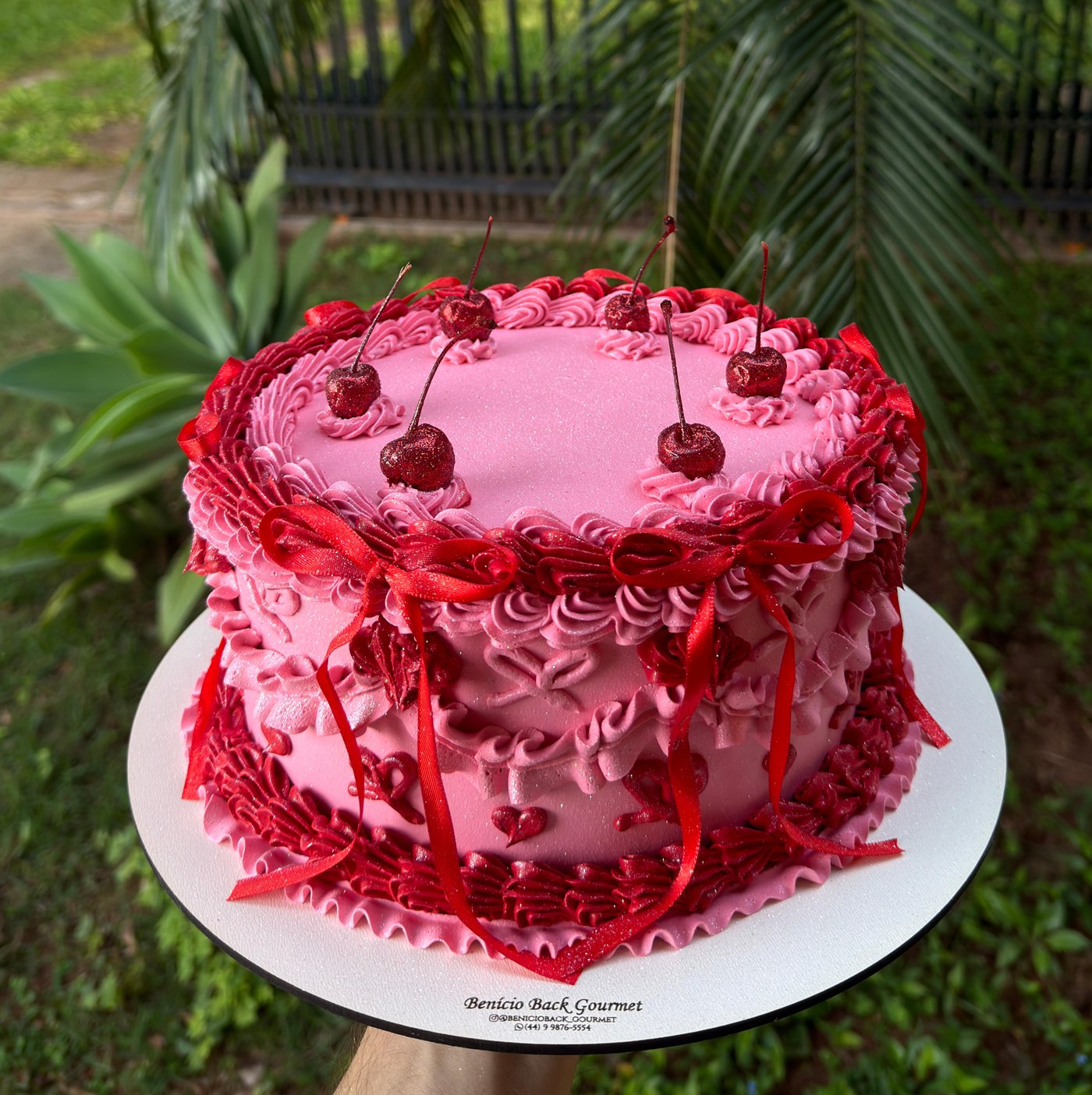 Bolo rosa com cerejas e laços vermelhos no estilo retrô