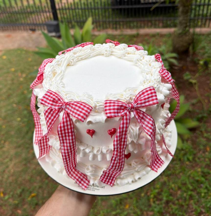 Bolo branco com laços xadrez vermelhos e coração